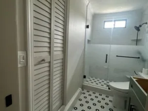 Bathroom renovation with tile upgrade showing closet doors and shower area